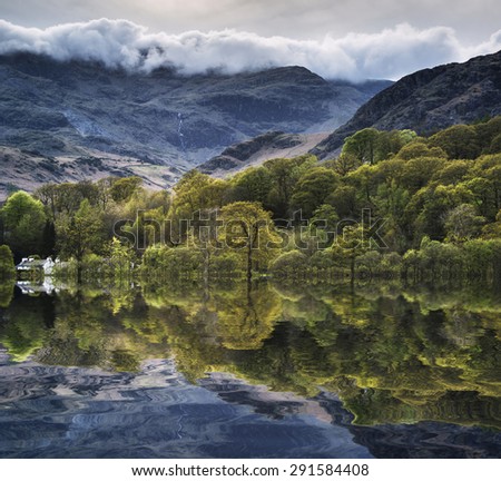 Forest landscape reflected in calm water of Coniston Water in Lake District