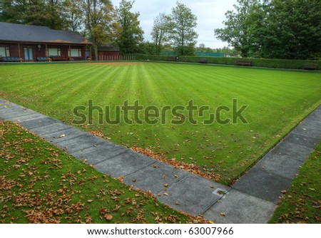Bowling green during Autumn Fall with leaves on striped mown lawn