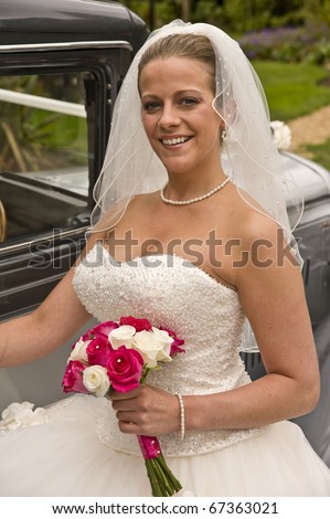 Portrait of attractive young bride getting into vintage wedding car