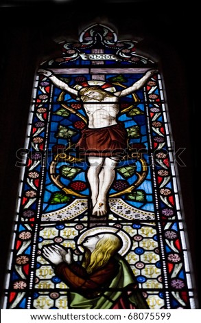 Beautiful stained glass window depicting Jesus on the crucifix with Mary at his feet