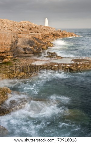 Waves crashing over rock formation cliffs at sunset with beautiful light on rock faces
