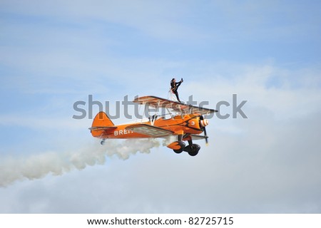 EASTBOURNE, ENGLAND - AUGUST 12 - Breitling female Wingwalker performs high kick in flight during performance at annual International Airshow on 12th August 2011 at Eastbourne in England
