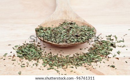 Chopped tarragon leaves on wooden serving spoon with shallow depth of field