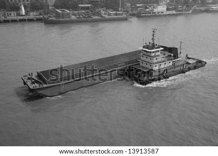 Tugboat pushing a barge in black and white