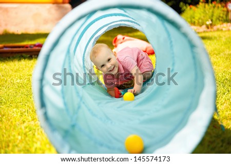 Adorable little girl playing inside a toy tunnel