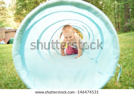 Adorable little girl playing inside a toy tunnel