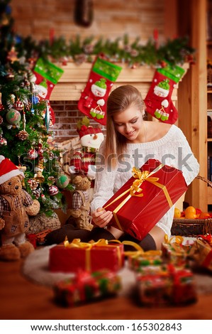 Beautiful woman with gifts under christmas tree