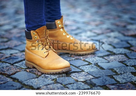 Close-up of feet in jeans and yellow boots