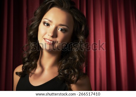 Portrait of a beautiful young woman against red curtain background