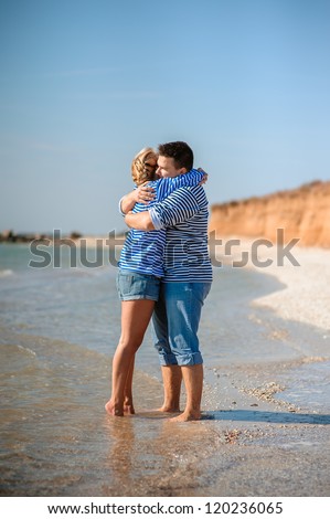 two people standing on the beach and hugging