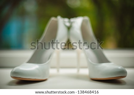 white wedding shoes with a bow on a heel on a green background