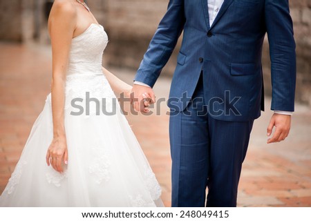 The groom in a blue suit holding the bride\'s hand