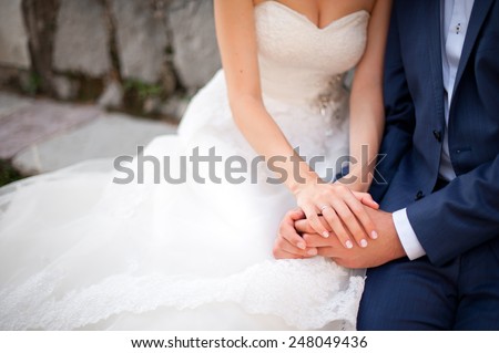 The groom in a blue suit holding the bride\'s hand