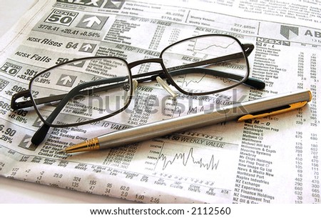 Pen and spectacles on financial page of newspaper