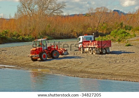 A digger and a truck collecting gravel for roading from river shore