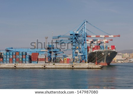 GENOA, ITALY - SEPTEMBER 13: Container ship JINHE (Built: 1997, Flag: Panama) is loaded with containers in Port of Genoa on September 13, 2009 in Genoa, Italy.