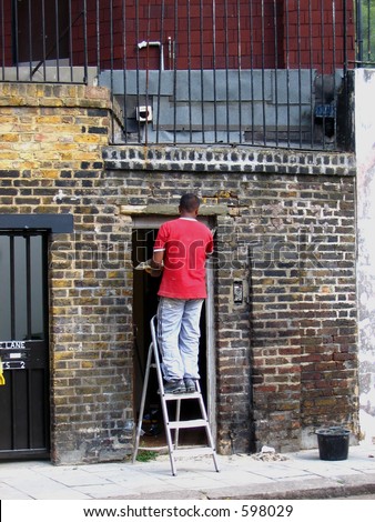 Handy man standing on a ladder outside a brick house
