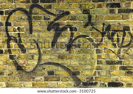 Real yellow brick old wall with plain graffiti. Background texture.