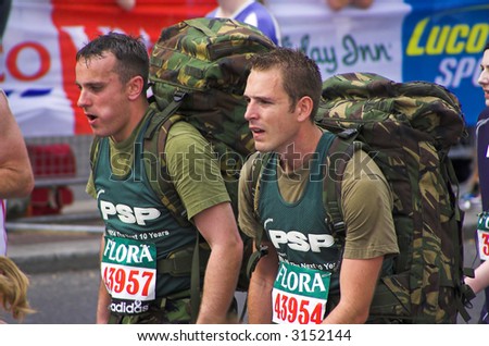 Exhausted participant in the London Flora marathon wearing military rucksacks.
