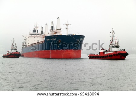 VARNA, BULGARIA - NOVEMBER 17: Cargo ship GENCO OCEAN (IMO: 9450739) is assisted by three tugboats on November 17, 2010 in Varna, Bulgaria. She is the newest ship to visit Port of Varna this year.
