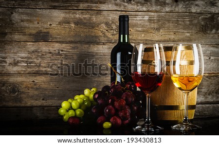 two glasses of wine with fresh grapes bottle and barrel in front of old grunge wooden planks two glasses of wine with fresh grapes bottle and barrel in front of old grunge wooden planks