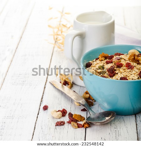 oatmeal with nuts and dried fruits on old white painted wooden table. Perfect breakfast