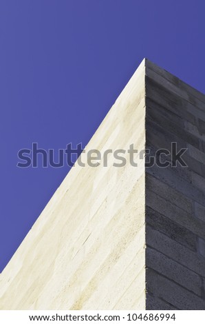 Urban yin and yang and yonder: Corner of building, one wall in sunlight and one in shade, under deep blue sky
