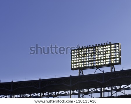 Floodlights over baseball stadium at dusk, with copy space