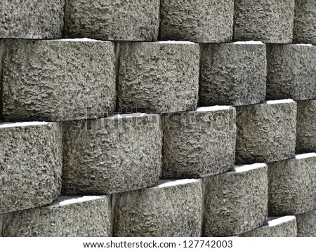 Wintry pattern of architecture and nature: Retaining wall of textured concrete blocks with snow in the same spot on each