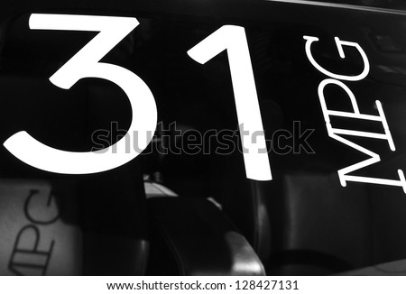 Sign of fuel efficiency on windshield of new car at auto show, in black and white