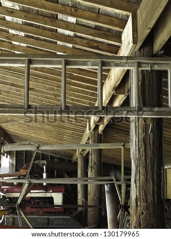 Interior of toolshed with old beams and aluminum, extension ladder by winter daylight on historical farm in northern Illinois