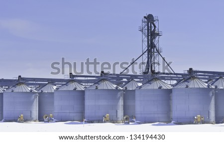 Steel grain silos and control tower above snow in March, central Illinois