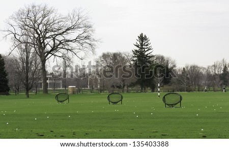 Three round target nets surrounded by golf balls on driving range in spring, northern Illinois
