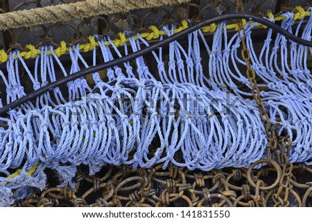 Industrial detail: Coiled blue rope by rusty links of iron net on trawler in harbor