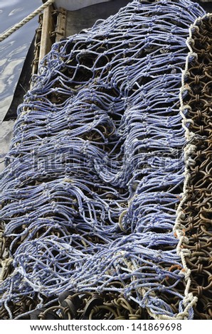 Pattern of knotted blue rope, part of net stowed aboard a fishing trawler