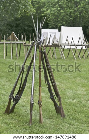 Muskets with bayonets stacked together in Union camp at reenactment of battle in American Civil War (1861-1865), Lombard, Illinois (selective focus)