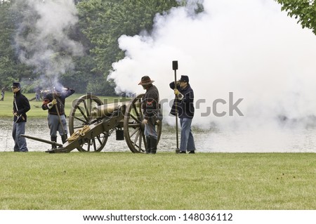 LOMBARD, ILLINOIS/USA - JULY 27: American Civil War (1861-1865) reenactment on July 27, 2013, in Lombard, IL. Smoke belches as four actors on the  Union side fire a cannon during a mock battle.