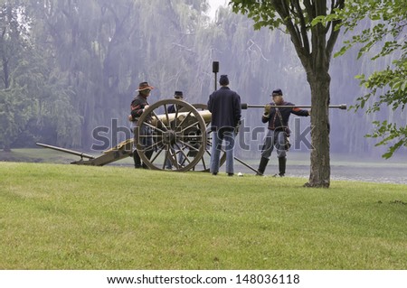 LOMBARD, ILLINOIS/USA - JULY 27: American Civil War (1861-1865) reenactment on July 27, 2013, in Lombard, IL. Actor-artilleryman prepares cannon round while Union compatriots wait  in smoky haze.