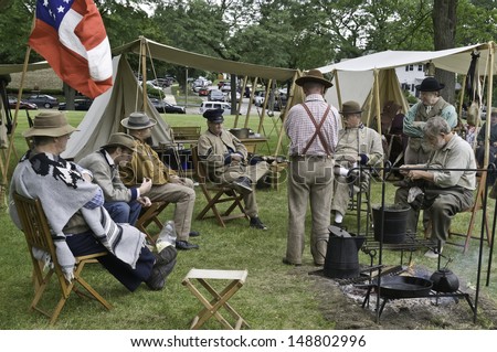 LOMBARD, ILLINOIS/USA - JULY 27: American Civil War (1861-1865) reenactment on July 27, 2013, in Lombard, IL. Rebel-actors relax in Confederate camp near a parking lot before a mock battle.