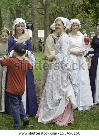 WHEATON, ILLINOIS/USA - SEPTEMBER 7: American Revolutionary War (1775-1783) reenactment on September 7, 2013, in Wheaton, IL. Young women actors in period dress socialize in military encampment.