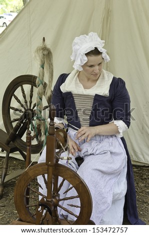 WHEATON, ILLINOIS/USA - SEPTEMBER 7: American Revolutionary War (1775-1783) reenactment on September 7, 2013, in Wheaton, IL. Young actor in period dress works at treadle wheel in military encampment.
