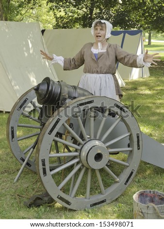 WHEATON, ILLINOIS/USA - SEPTEMBER 7: American Revolutionary War (1775-1783) reenactment on September 7, 2013, in Wheaton, IL. Woman actor in period dress gives a talk in shade of military encampment.