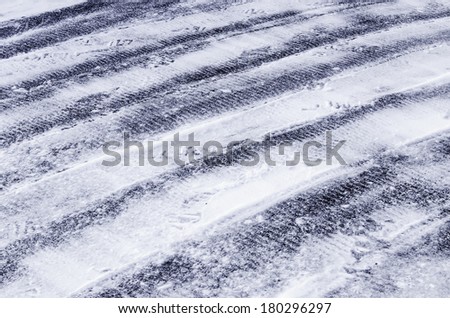 Winter abstract: Rows of tread marks from tires of small plow in snow on asphalt driveway in northern Illinois