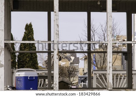 WASHINGTON, ILLINOIS, USA - MARCH 21, 2014: Four months after a tornado destroyed entire neighborhoods here, severe structural damage to houses remains visible through a neighbor\'s porch.