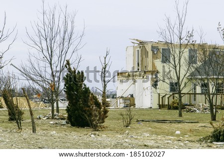 WASHINGTON, ILLINOIS, USA - MARCH 31, 2014: In the aftermath of a November tornado, signs of recovery appear as a robin perches on a bare tree (at left) amid scenes of destruction and reconstruction.