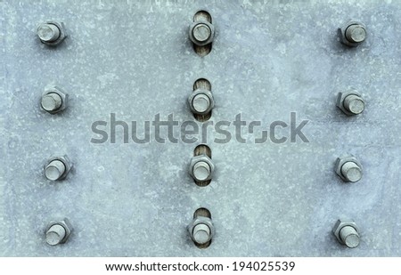 Rows of bolts holding a gray metal plate in place against wood outdoors