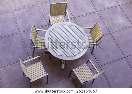 Geometric patterns for casual conversation outdoors: High angle view of wooden round table and five outdoor chairs on large flagstone patio in the American Southwest