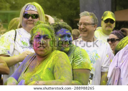 LAKE ZURICH, ILLINOIS, USA - June 20, 2015: Two women revelers stand doused in colored powder while they wait to start a 5K \