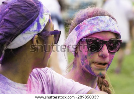 LAKE ZURICH, ILLINOIS, USA - June 20, 2015: A woman with colored powder on her sunglasses and face shares a moment with another doused participant after a 5K \