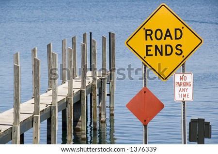 Pier and yellow ROAD ENDS sign by water